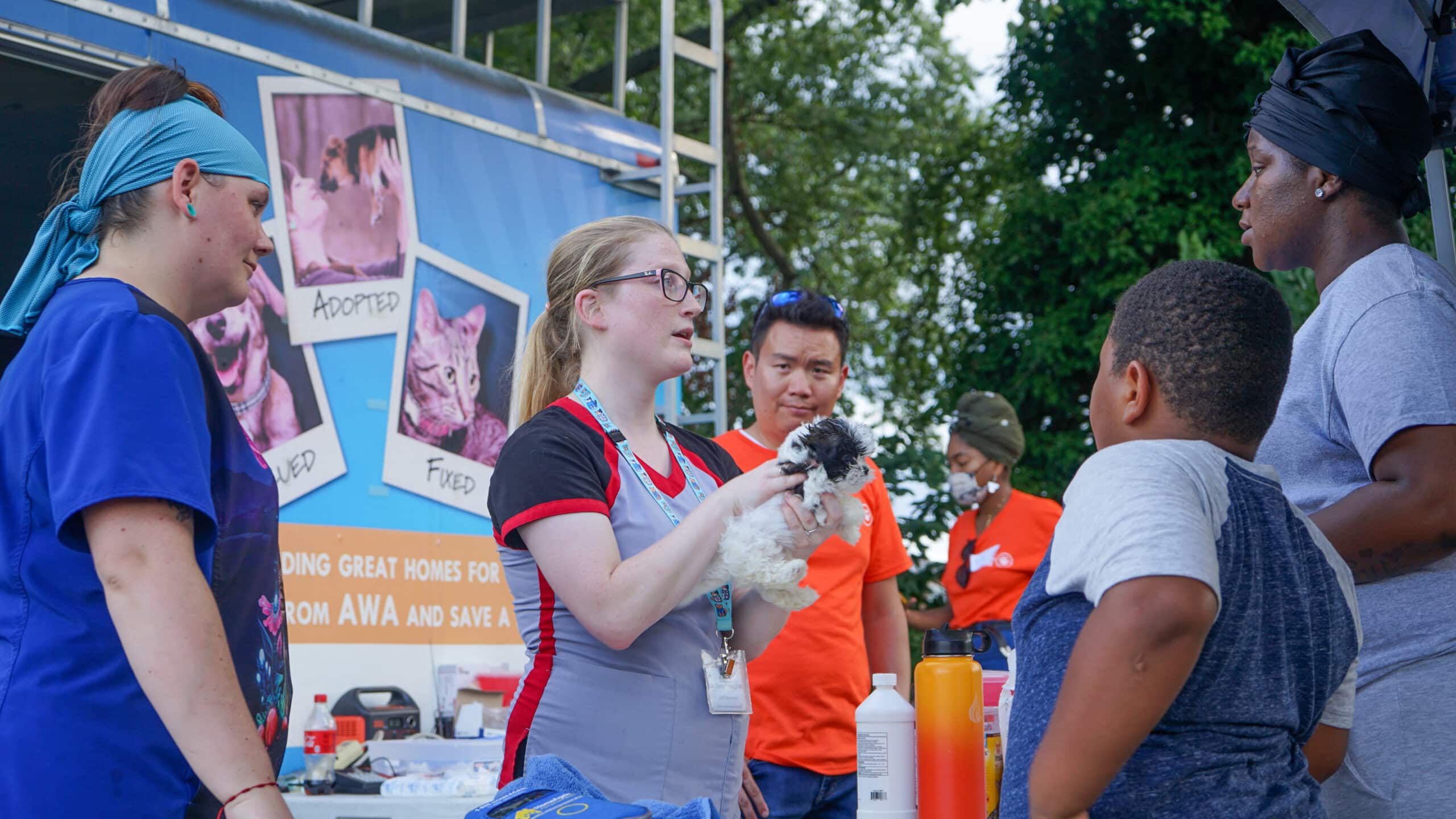 Dr. Emily holding dog and speaking with community at Animal Welfare Association Vets on Wheels event.