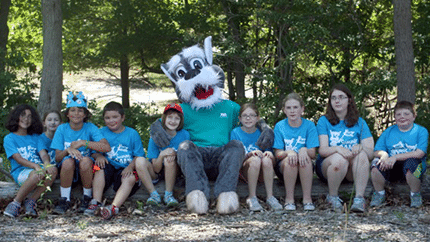 Children attending summer camp at Animal welfare Association sitting with camp mascot.