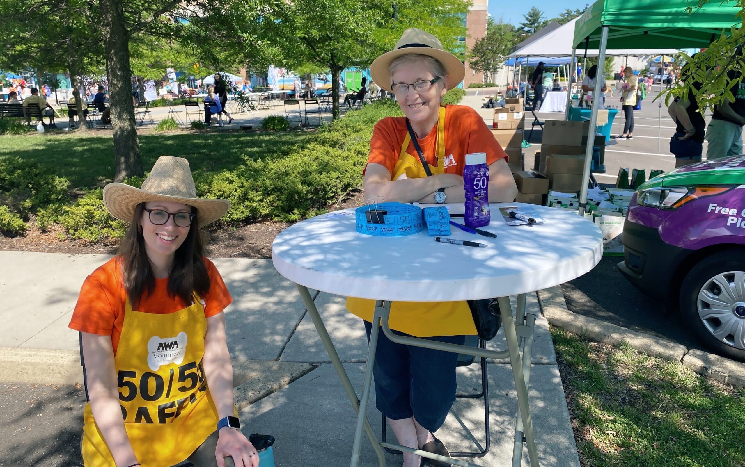 2 volunteers standing at table at AWA Paws & Feet 2022.