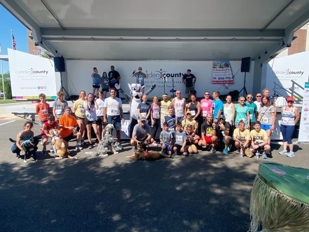 Winners of 2022 Paws & Feet 5k Run/ Walk in front of stage after receiving awards.