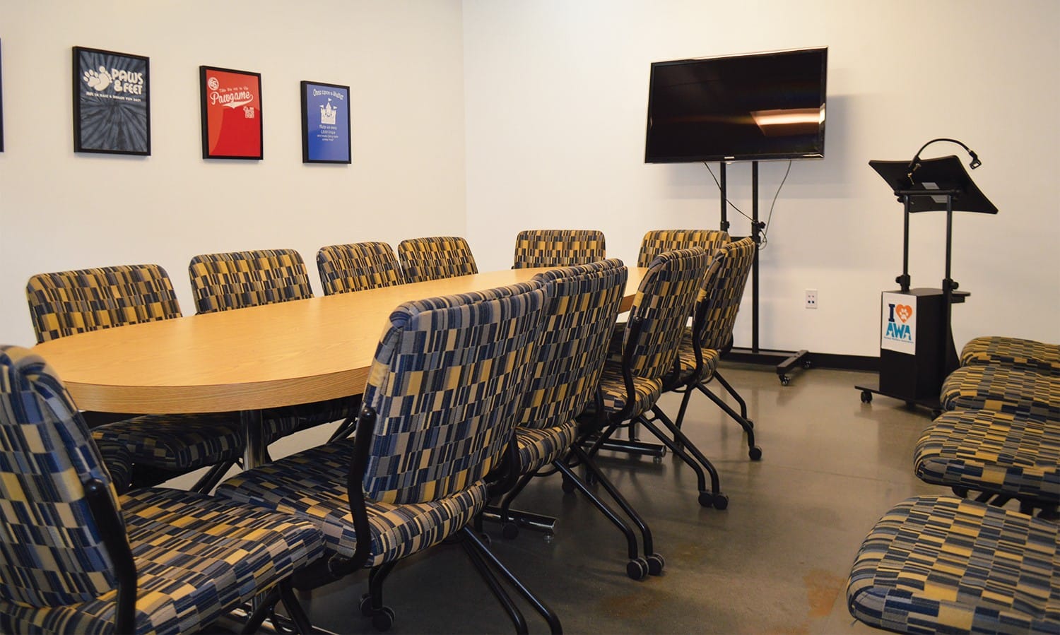 Conference table, chairs, monitor and lectern in Animal Welfare Association conference room for event rental.