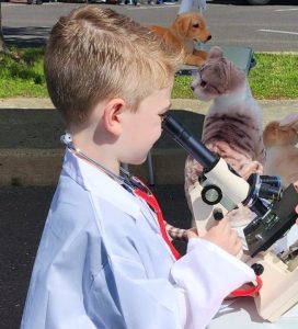 Child looking into microscope during Vet Pretend Play Experience at Animal Welfare Association.