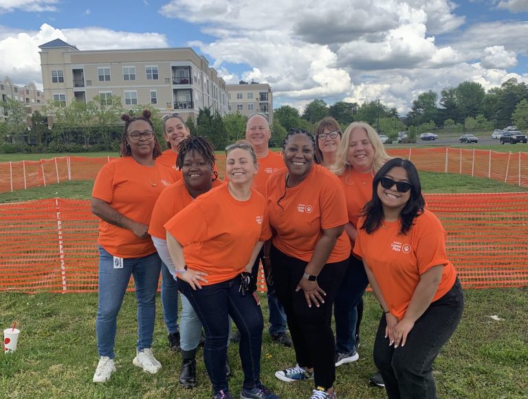 Volunteers in orange shirts taking picture at AWA Paws & Feet 2023.