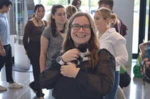 Woman in lobby of office smiling and holding black and white kitten.