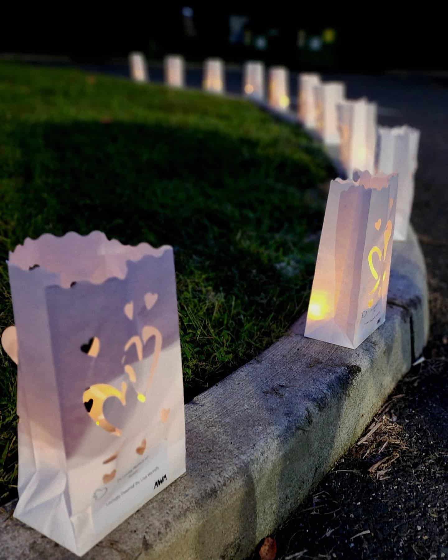 White luminary bags with candles inside balance on a curb line.