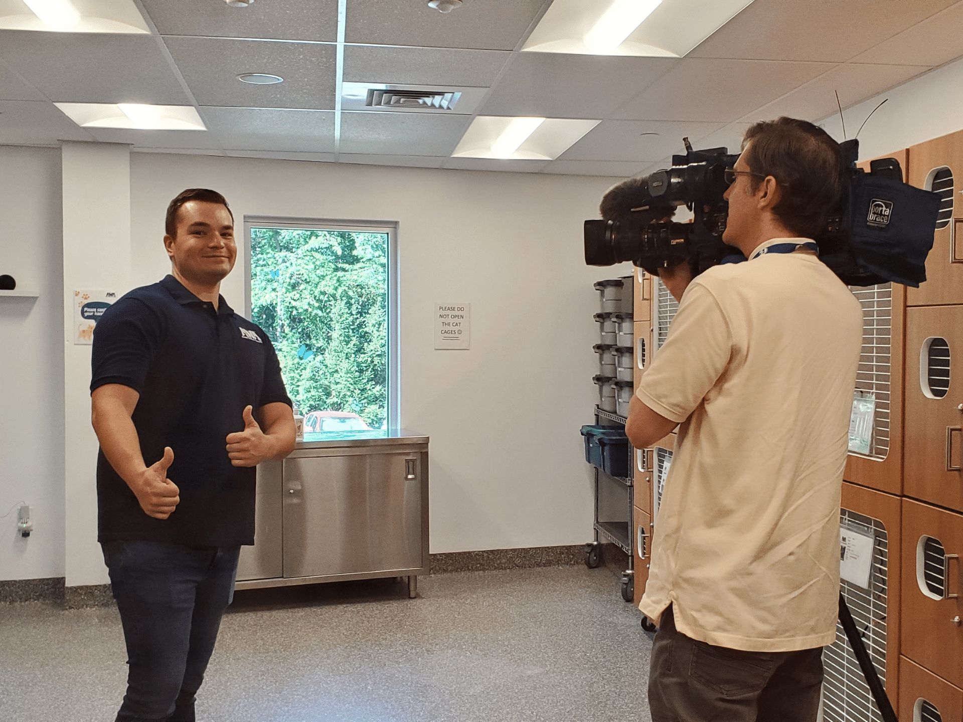 Caucasian male (Cole) giving the thumbs up while a man with a news camera films him.