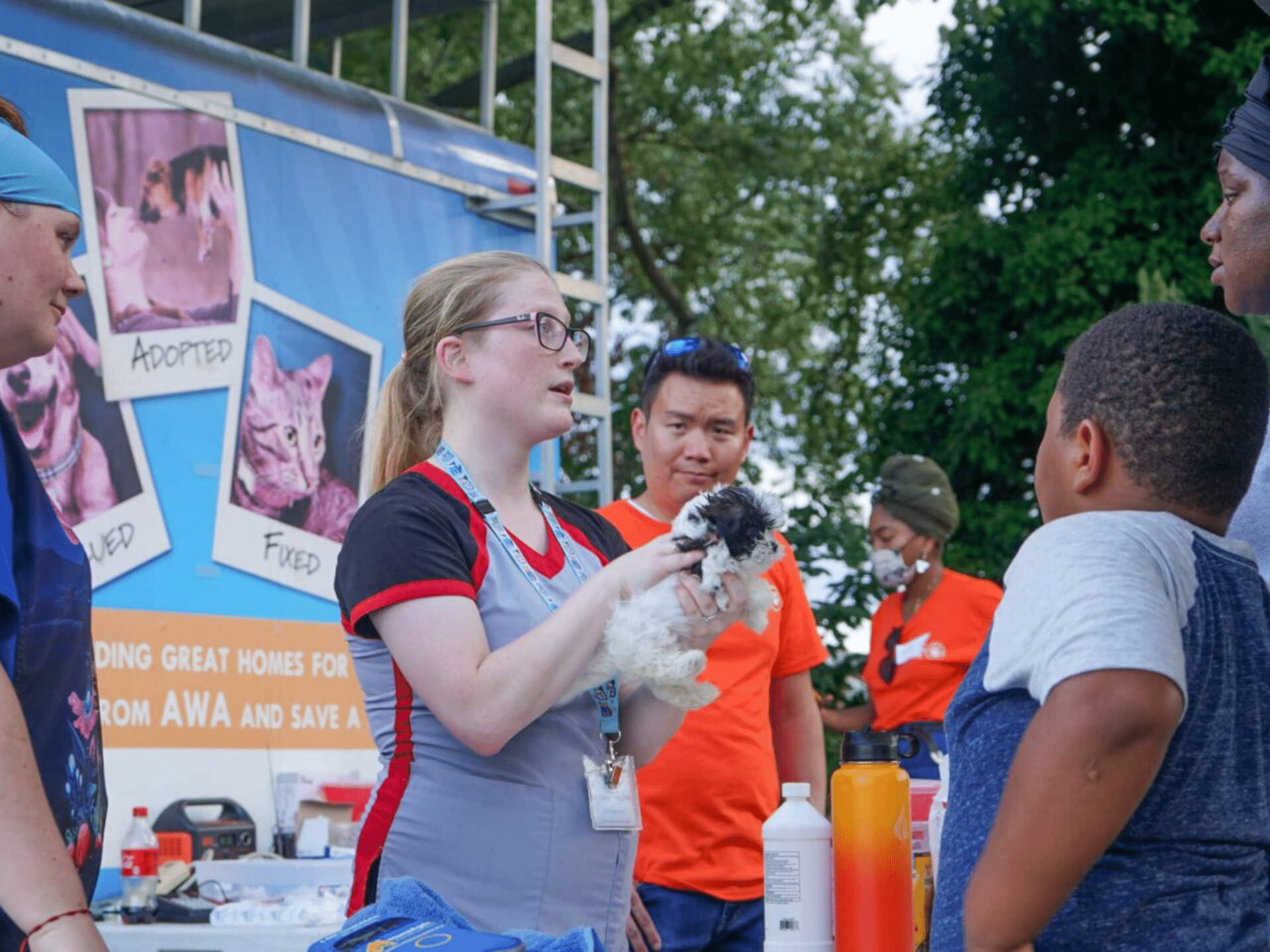 Veterinarian holding dog speaking with family at Animal Welfare Association Vets on Wheels.